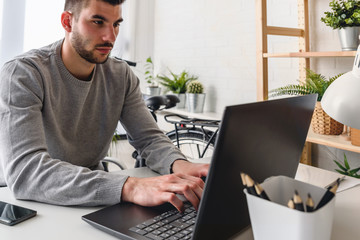 Student using laptop computer while sitting at desk at home. Distance learning