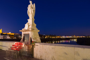 Cordoba,Spain,2,2014;Candles and statue of the Archangel of St. Gabriel on the Roman bridge.