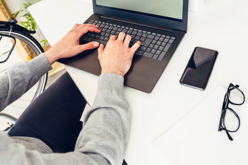 Man using laptop computer while sitting at desk in office. Top view. Overhead shot.