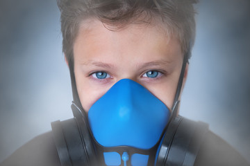 Young boy wearing gasmask, respirator portrait. Effects of worldwide air pollution, industrial...