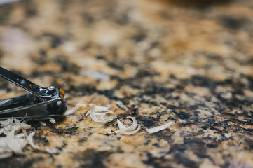 Pile of fingernail and toenail clipping next to a metal cutter