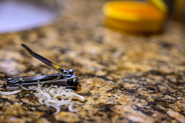 Pile of fingernail and toenail clipping next to a metal cutter