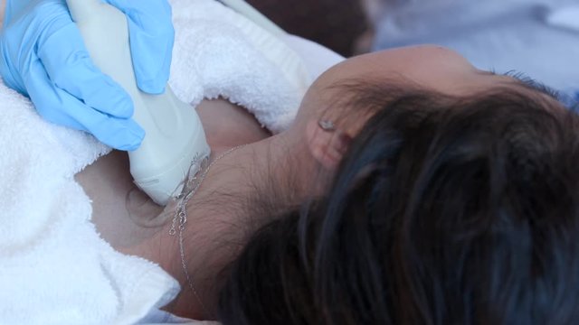 CU sonographer scans woman's neck