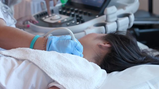 Medium sonography student scans woman's neck