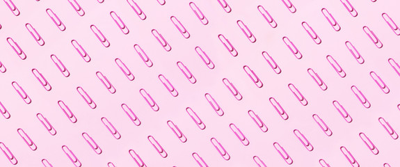 Pattern of pink paper clips on pastel pink background. Top view. Flat lay. Back to school. Office, business, paperwork, education concept. Banner