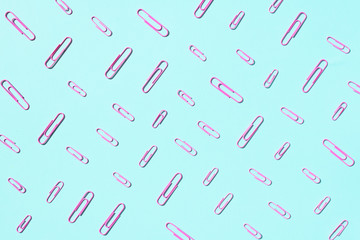 Colored paper clips on pastel blue background. Top view, flat lay. Back to school concept. College, institute education, office work