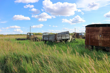 Fototapeta na wymiar Rusty abandoned trucks in the field under blue sky