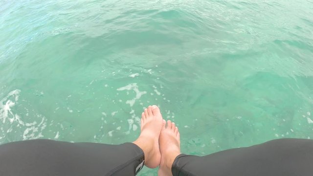 point Of view man sit on the boat hanging legs with diving suit 