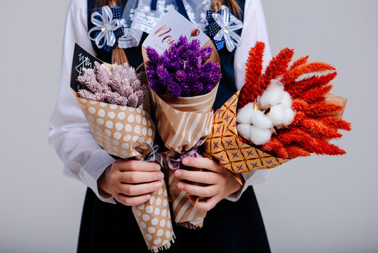 A three small bouquet of Phalaris and Amaranthus and cotton bolls in the hands of girl