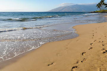 footprints in the sand on shore of  ocean water 