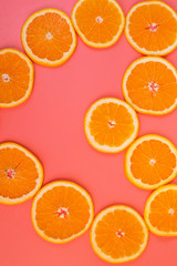 Background of sliced ripe oranges on a pink background vertical.