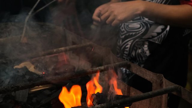 Close-up medium shot of people preparing a barbeque fire in a grill