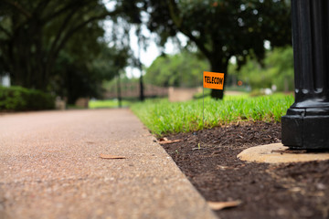 Telecommunications, cable line stake flag beside a light post 