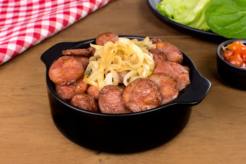 Sliced and fried Calabrese sausage in a pub table in wood background 