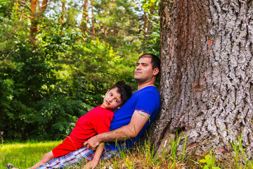 father and son resting under a tree in the summer
