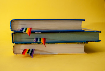 a stack of three books with rainbow ribbon bookmarks is on the table. Concept back to school,...