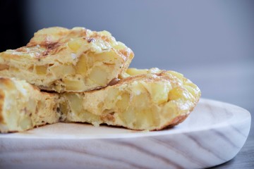 close up of a sliced portion of spanish omelet on a wooden plate