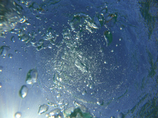 Underwater bubbles with sunlight through water surface as seen in natural scene at Caribbean turquoise open ocean sea