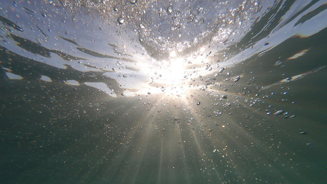 Fototapeta Underwater bubbles with sunlight through water surface as seen in natural scene at Caribbean turquoise open ocean sea