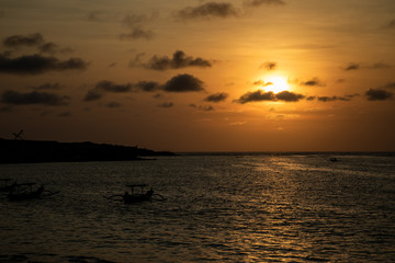 Naklejka na ściany i meble Dark orange sunset view over the beach with a boat in Bali
