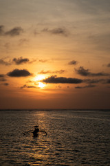 Fototapeta na wymiar Dark orange sunset view over the beach with a boat in Bali