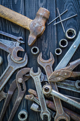Rusty old tools are laid out on black vintage wood background.
