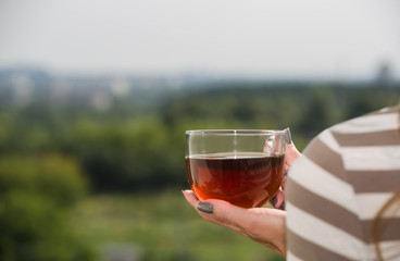 Nature view with female hand holding cup of tea