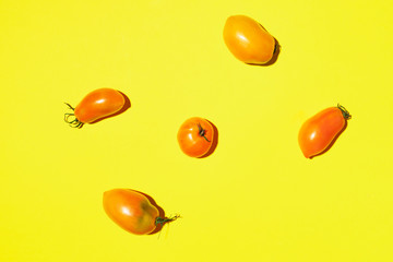 Yellow tomatoes pattern on bright background. Flat lay, top view. Summer minimal concept. Vegan and vegetarian diet