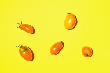 Yellow tomatoes pattern on bright background. Flat lay, top view. Summer minimal concept. Vegan and vegetarian diet