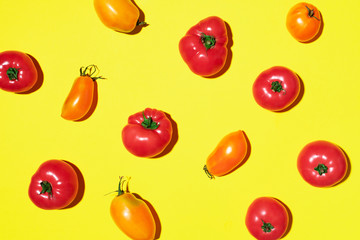Yellow and red tomatoes pattern on yellow background. Flat lay, top view. Summer minimal concept. Vegan and vegetarian diet.