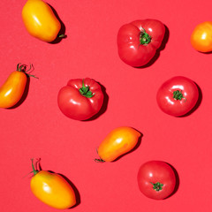 Yellow and red tomatoes pattern on red background. Flat lay, top view. Summer minimal concept. Vegan and vegetarian diet.