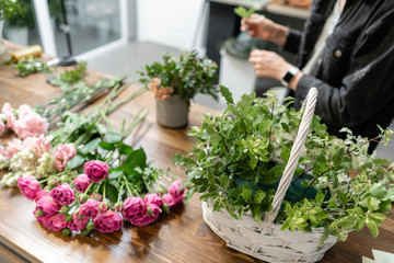Woman florist create flower arrangement in a wicker basket. Beautiful bouquet of mixed flowers. Floral shop concept . Handsome fresh bouquet. Flowers delivery