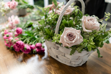 Woman florist create flower arrangement in a wicker basket. Beautiful bouquet of mixed flowers. Floral shop concept . Handsome fresh bouquet. Flowers delivery