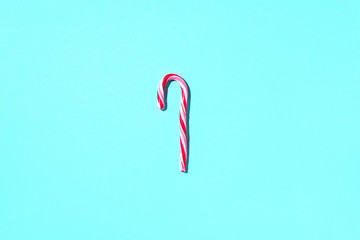 Fototapeta premium Christmas candy cane on blue background with copy space. Top view. Greeting card on Christmas and New Year. Minimal festive concept