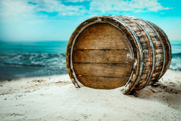 Old wooden barrel on the sandy beach with dark blue ocean view.