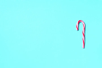 Christmas candy cane on blue background with copy space. Top view. Greeting card on Christmas and New Year. Minimal festive concept