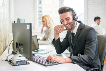 Smiling customer support phone operator talking with a client in call centre