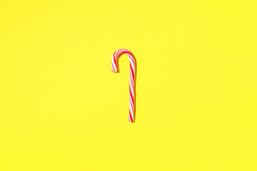 Obraz premium Christmas candy cane on yellow background with copy space. Top view. Greeting card on Christmas and New Year. Minimal festive concept