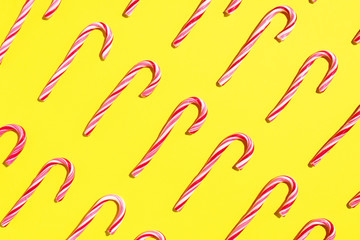 Pattern of Christmas candy cane on yellow background. Top view. Flat lay. Creative minimal concept. Greeting card on Christmas and New Year. Art composition.