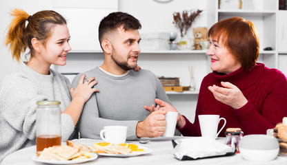 Cheerful elderly mother with adult children drinking tea