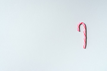 Fototapeta premium Christmas candy cane on grey background with copy space. Top view. Greeting card on Christmas and New Year. Minimal festive concept