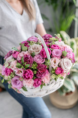 Flower arrangement in Wicker basket. Beautiful bouquet of mixed flowers in woman hand. Floral shop...
