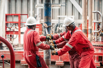 Employees holding chain attached to a pipe