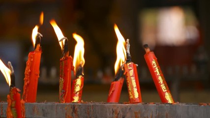 Video 4k of close-up flame from burning red chinese candle in the temple