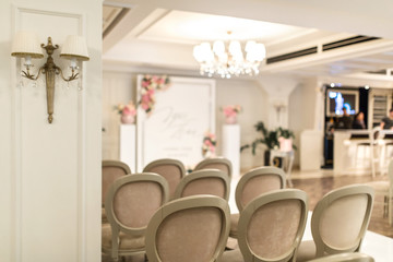 Wedding Hall. Rows of white festive chairs for guests. Wedding arch for the bride and groom.
