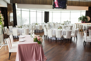The wedding table setting for the newlyweds is decorated with fresh flowers of carnation, rose, anthurium and eucalyptus leaves. Silver candlesticks, white candles. Wedding floristry. Closeup details