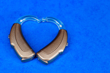 hearing aids on blue background close-up, heart shape.