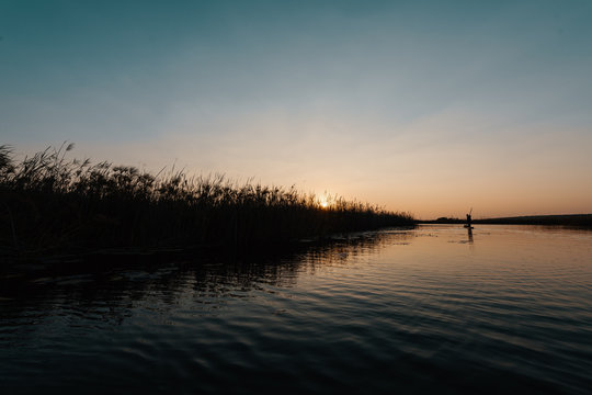 Man poling a dugout canoe at sunset in Cuando river