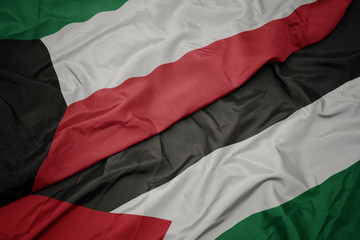 waving colorful flag of palestine and national flag of kuwait.