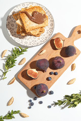 Figs, pear and blueberries and toasts with chocolate on a cutting wooden board.